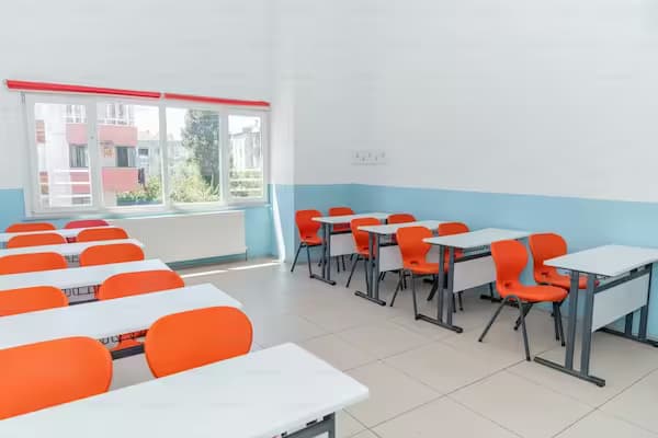 Sală de clasă cu bănci școlare albe și scaune portocalii